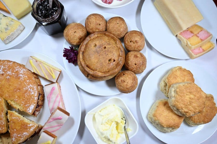 Table with British food - pie, scones, cheese and cakes