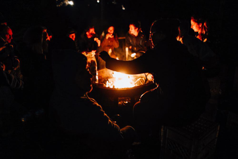 People sitting round a firepit toasting marshmallows